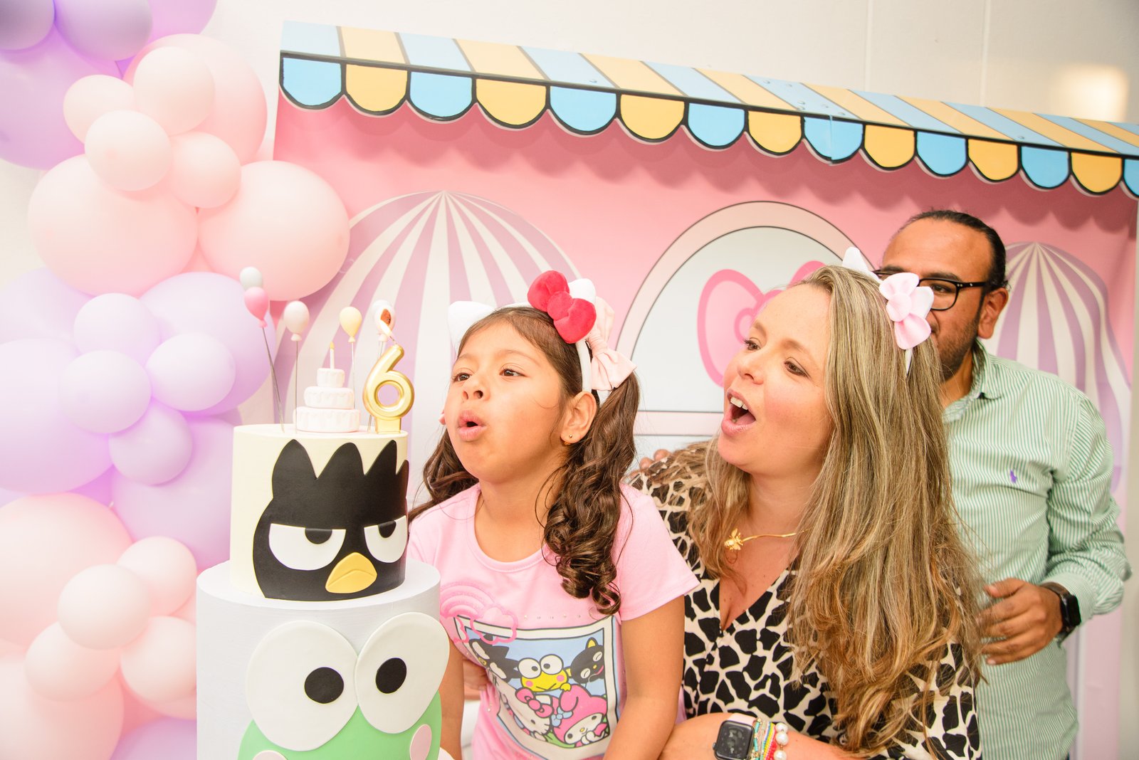 Cumpleaños infantil con pastel y decoración temática en Diversitopia; niña soplando velas acompañada de su familia.
