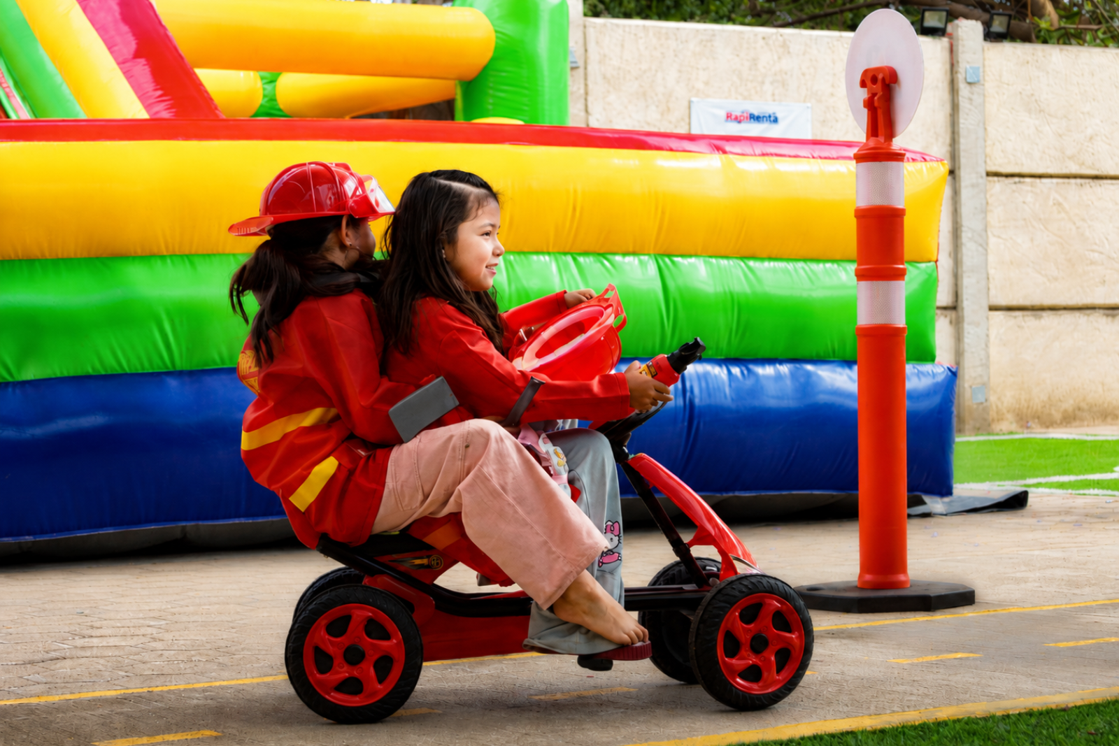 Niñas jugando en la pista de autos frente al inflable de Diversitopía en Oaxaca.