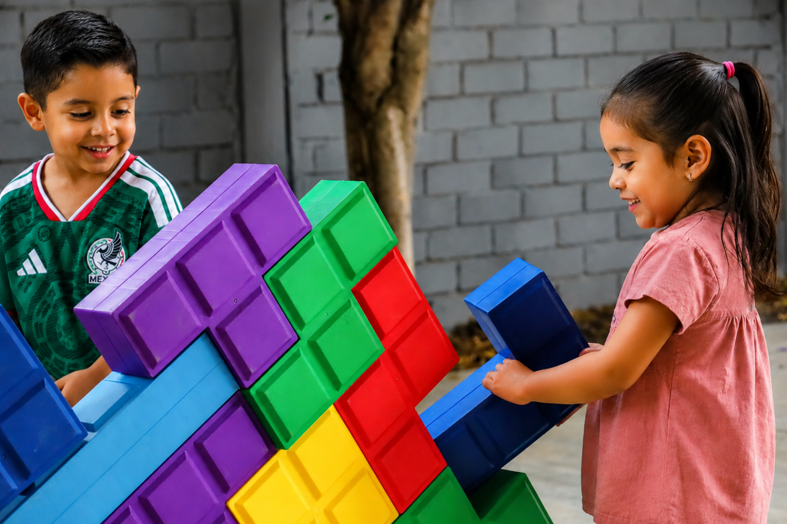 Niños jugando con bloques gigantes de colores en el área infantil de Diversitopía.